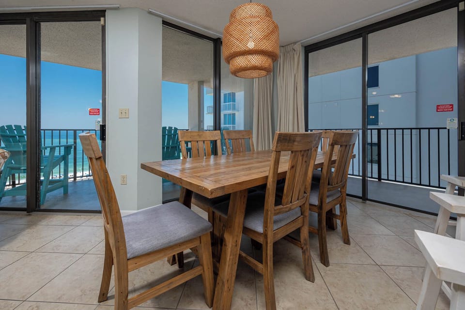 Gather around the rustic wooden dining table, enjoying views and natural light from the beachfront balcony