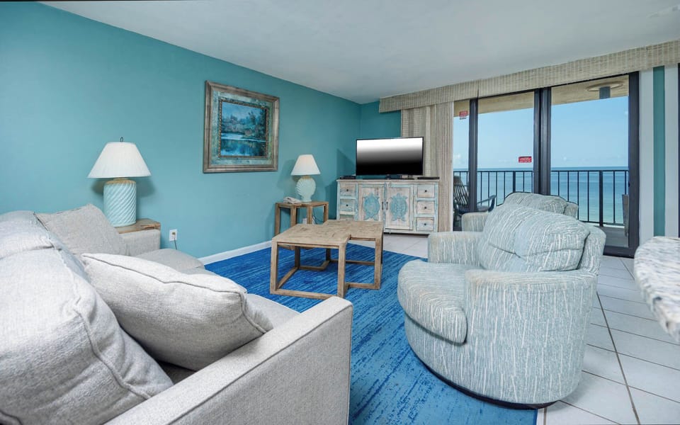 The living area features a cozy sofa with queen sleeper, stylish accent chairs, a flat-screen TV, and stunning views