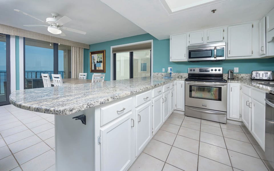 This kitchen features stainless appliances, granite countertops, and a dining area with a beautiful beach view