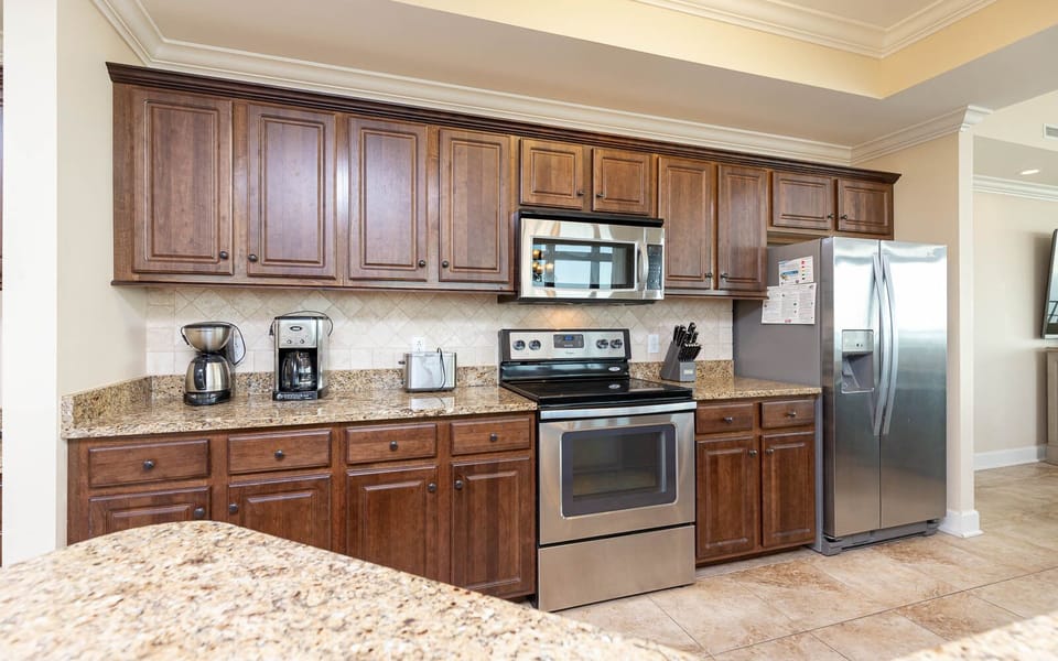 The kitchen features wooden cabinetry, stainless appliances, and multiple coffee makers for a delightful culinary experience