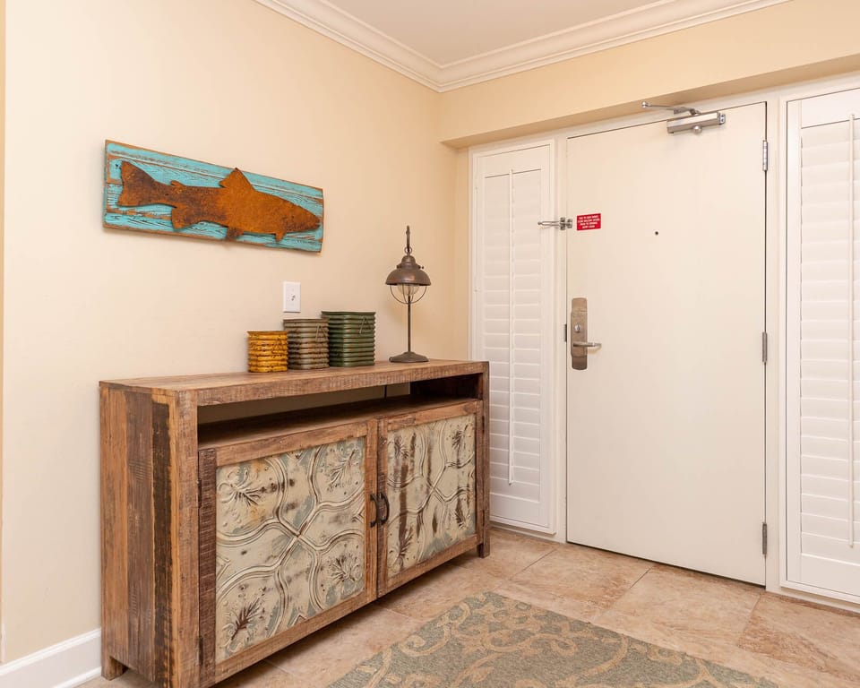 The entryway features a rustic console table with decorative accents and a charming fish artwork, setting a relaxed tone