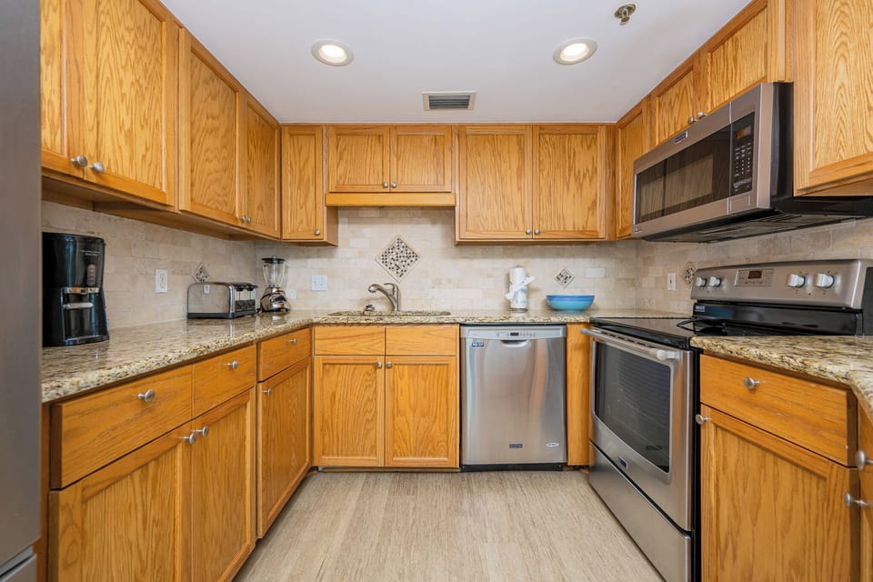 Warm wood cabinetry complements the granite countertops in this inviting kitchen, featuring modern appliances