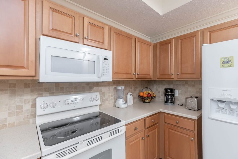 Prepare meals in this functional kitchen featuring ample counter space, white appliances, and a welcoming fruit basket