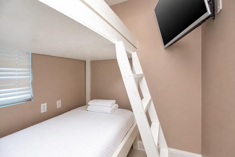 This cozy bunk room features a bunk bed, fresh linens, and a wall-mounted TV for entertainment