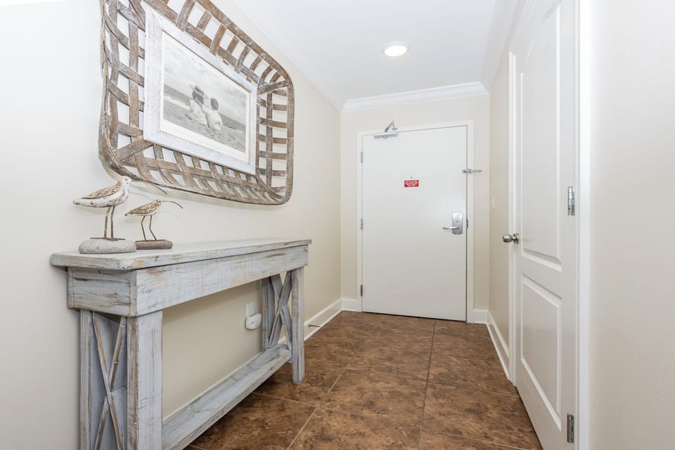 Step into a welcoming entryway featuring coastal decor, a stylish console table, and charming bird sculptures