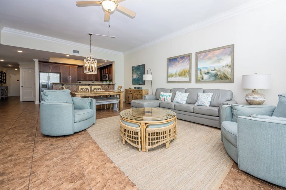 Relax in the airy living space, featuring comfortable seating, a stylish coffee table, and beautiful coastal artwork