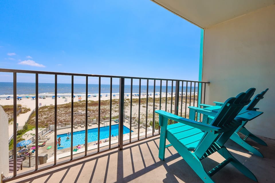 Enjoy relaxing beach views from this balcony, featuring comfortable seating and a glimpse of the pool below