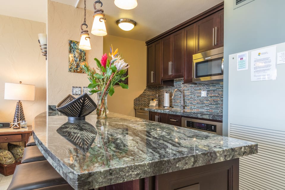 Your fully equipped kitchen features rich cabinetry, granite counters, stylish tile backsplash, and modern appliances—everything you need to create meals comfortably during your stay.