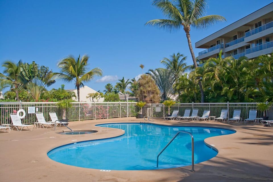 Sparkling pool surrounded by swaying palms and sunny skies—your perfect spot to unwind under the tropical sun, with loungers ready for lazy afternoons.