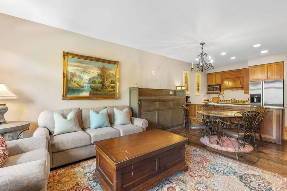 Unwind in your open-concept living area with plush seating, a full kitchen, and warm wood accents that create a cozy, home-away-from-home feel.