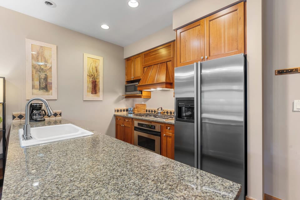 Your fully equipped kitchen features gleaming granite countertops, stainless steel appliances, and rich wooden cabinetry—perfect for preparing your favorite meals during your stay.