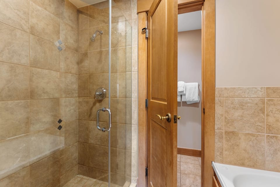 Step into your private bathroom, where elegant tiled walls and a spacious glass-enclosed shower await your refreshing retreat after a day of adventure.