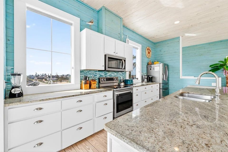 Cook with stunning coastal views from this bright turquoise kitchen, complete with granite counters and modern appliances.