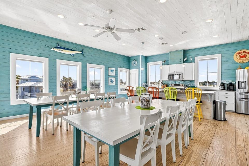 Your cheerful coastal kitchen welcomes family gatherings with colorful chairs, ample counter space, and bright windows framing island views.