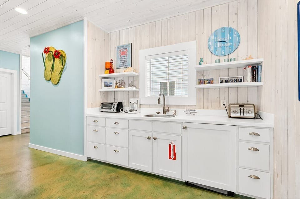 Your beach-inspired kitchen features white cabinetry, modern appliances, and coastal charm with cheerful turquoise accents that make cooking feel like a vacation.