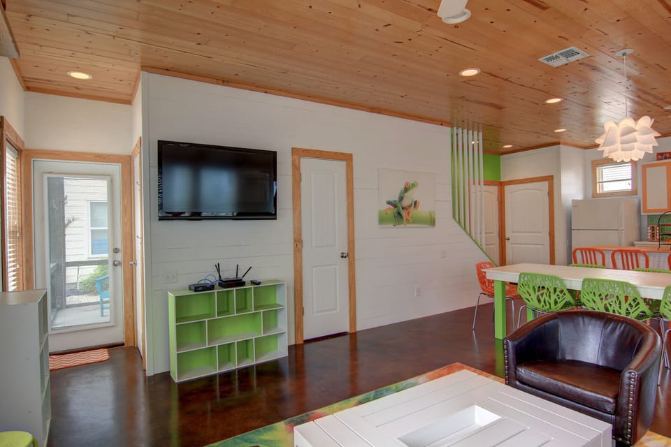 Relax in your bright living space with wood beam ceilings, flat-screen TV, and colorful modern furniture for comfortable indoor moments.