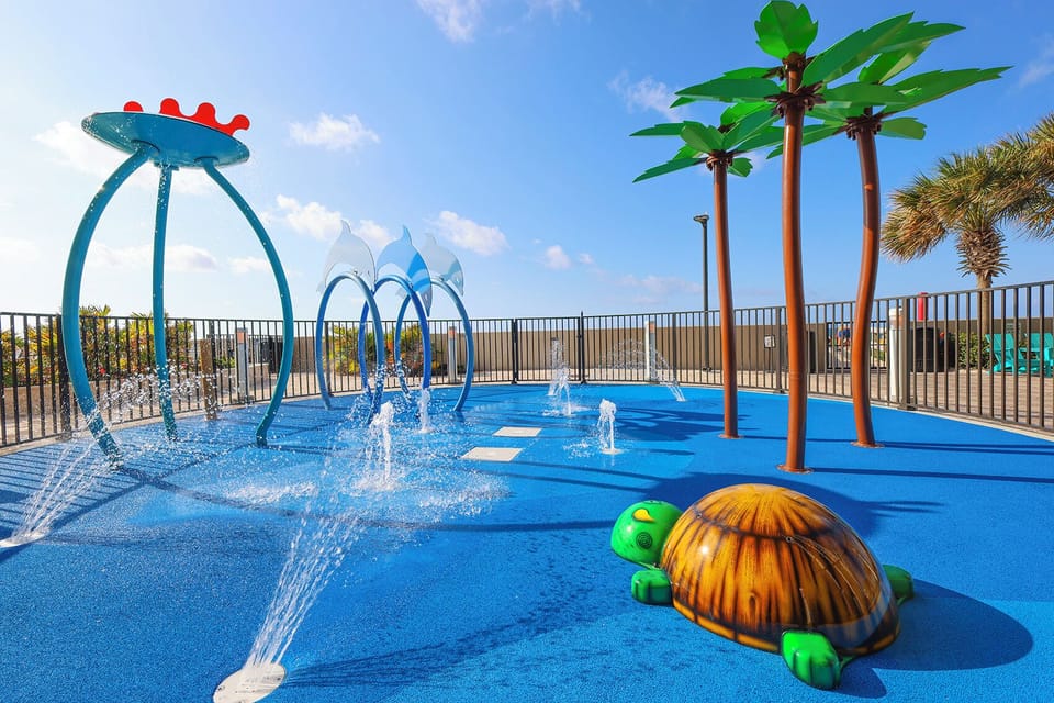 Splash around in this fun water splash pad at The Oasis featuring colorful fountains, playful turtles, and palm trees