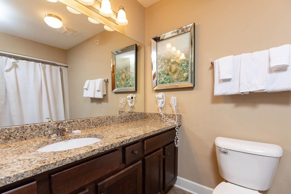 This guest bath features a stylish granite countertop, plush towels, and a bright mirror, ensuring a refreshing experience
