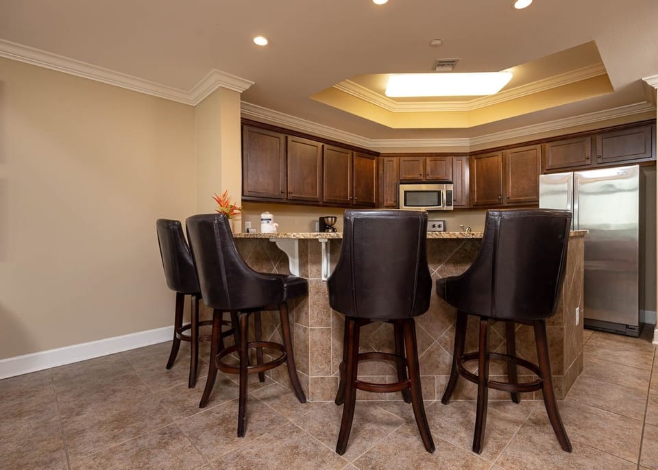 This kitchen features wood cabinets, granite countertops, and a breakfast bar with stylish seating, perfect for casual dining