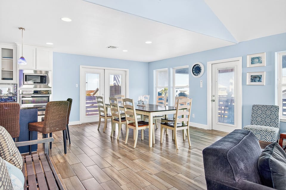 Gather around your spacious dining table where coastal charm meets comfort, with soft blue walls and gleaming floors creating the perfect backdrop.