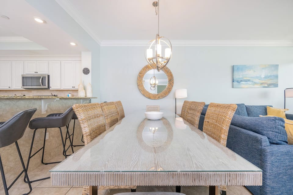 Dine at the stylish table with woven chairs, surrounded by light and a view into the inviting living area