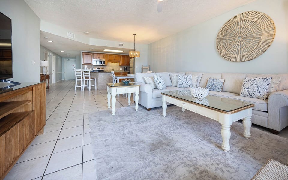 Spacious living area with a sofa with queen sleeper, beach balcony access, and a view of the dining space and kitchen
