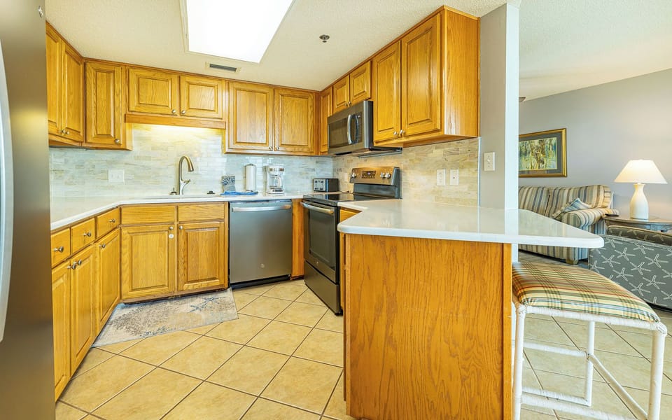 Warm wooden cabinets adorn the kitchen, featuring a coffee maker, sleek style, and ample storage