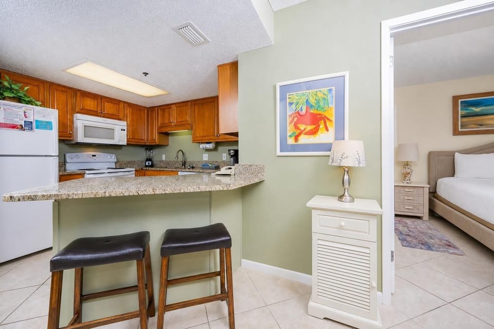 Warm wood cabinetry complements the modern kitchen's granite countertops, featuring a breakfast bar and a cozy seating area
