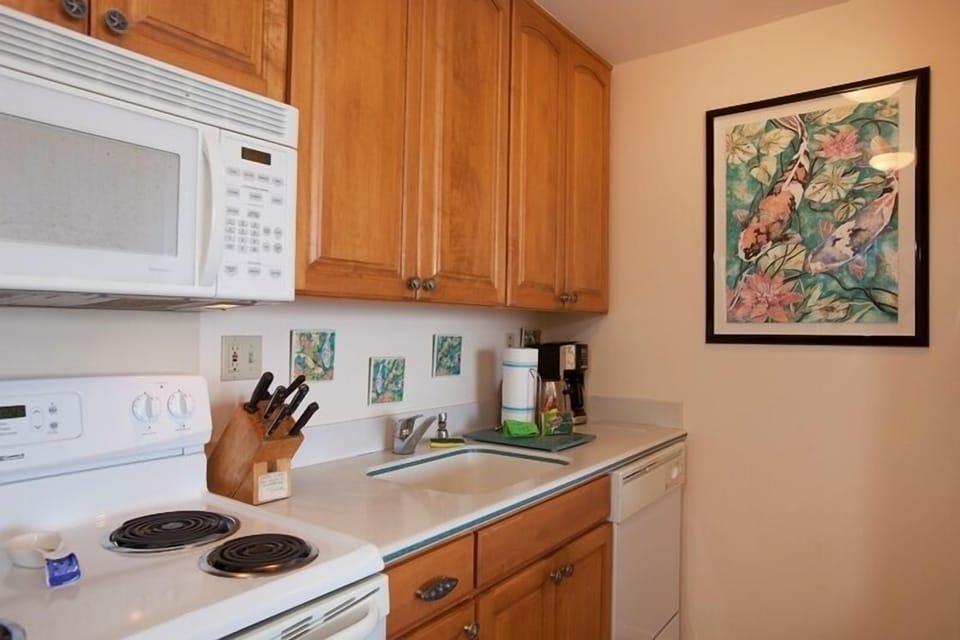 Your fully equipped kitchen features warm wood cabinets, modern appliances including microwave and dishwasher, and a cozy breakfast counter perfect for preparing meals during your stay.