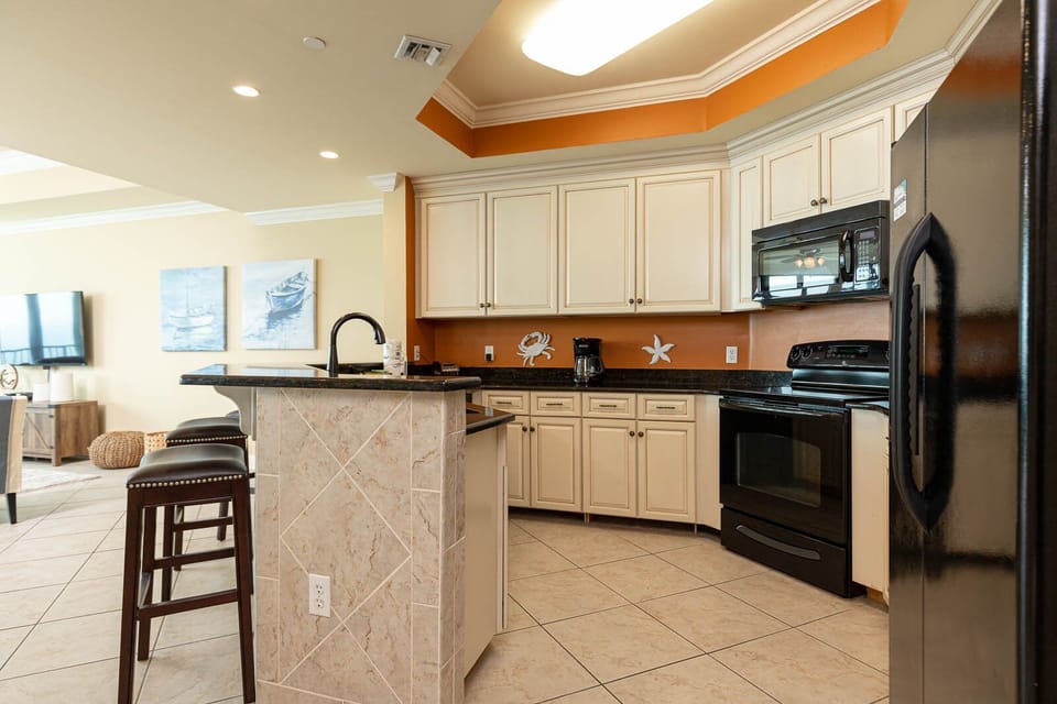 Prepare meals in this kitchen with elegant cabinetry, black appliances, and spacious countertops