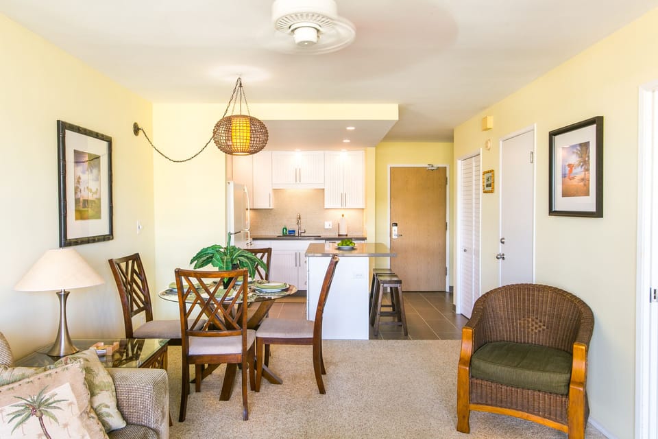 Step into your bright, cheerful retreat where warm yellow walls and tropical accents make you feel instantly at home. Relax in the woven chair or gather around the dining table while the open kitchen invites you to whip up your favorite island-inspired mea