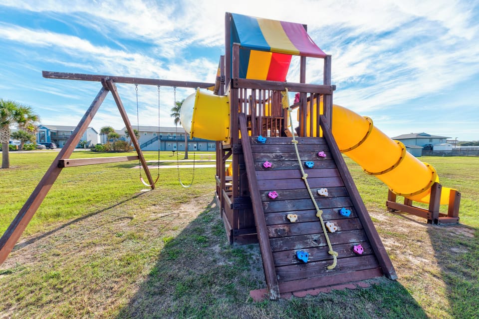 Adventure awaits at this colorful playground with swings, climbing wall, and twisting slide - perfect for your little explorers!