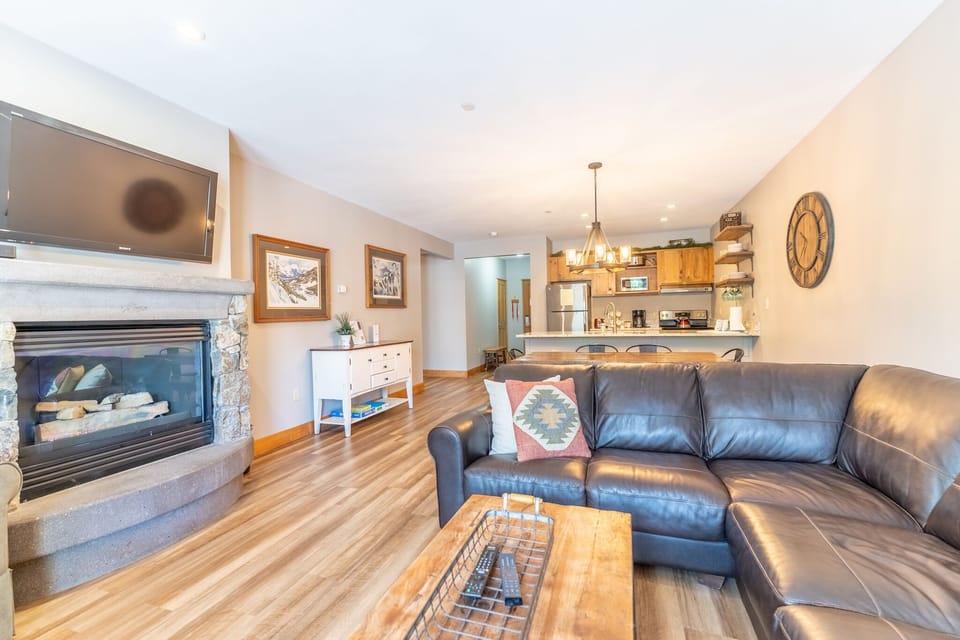 Unwind in your open-concept living space with plush leather seating, crackling fireplace, and fully equipped kitchen—perfect for cozy evenings.