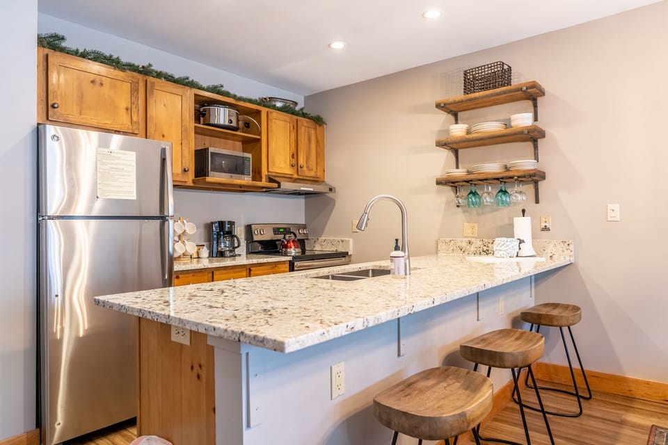 Your fully equipped kitchen features granite countertops, stainless appliances, and rustic bar seating perfect for morning coffee or casual meals.