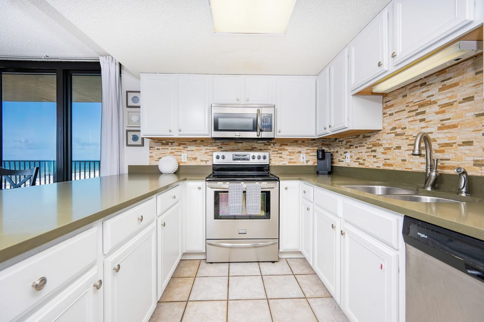 Prepare meals in the inviting kitchen featuring stainless appliances, ample counter space, and a view of the beach