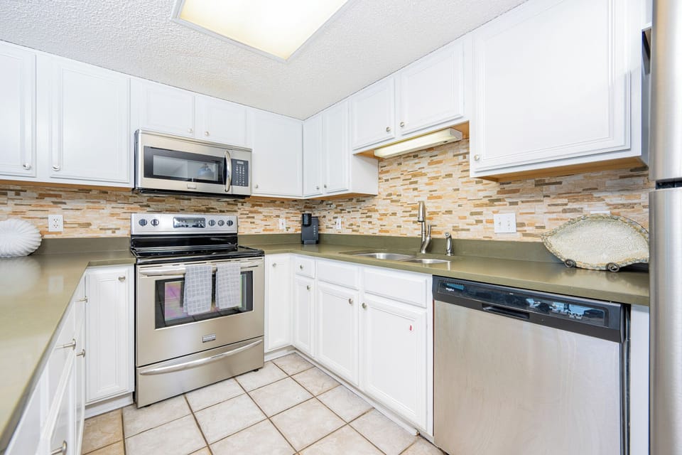 Cook in the stylish kitchen featuring stainless appliances and a decorative stone backsplash for added charm