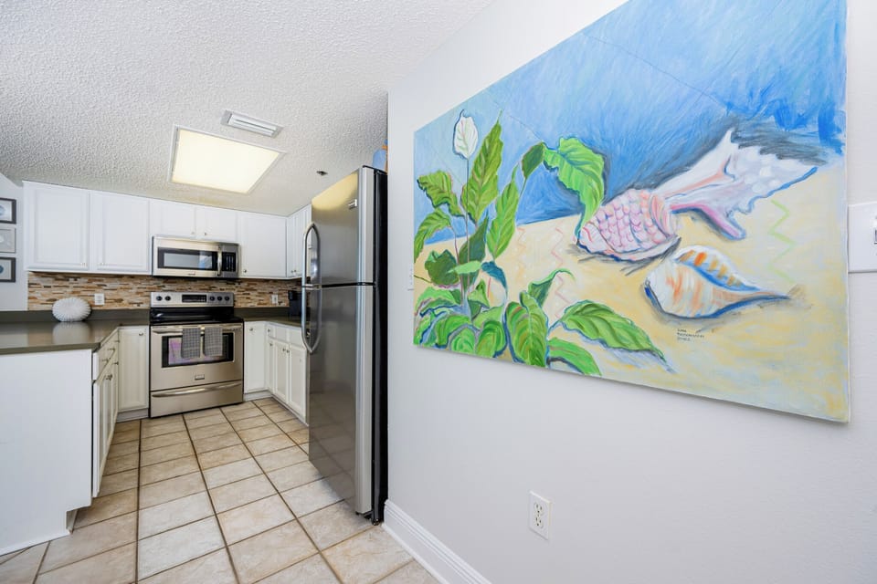 Cook and socialize in the bright kitchen, featuring stainless appliances and vibrant coastal artwork