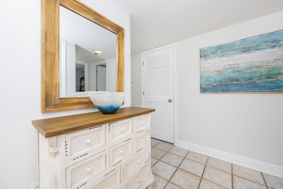 Step into a welcoming entryway featuring a stylish dresser, decorative bowl, and coastal art