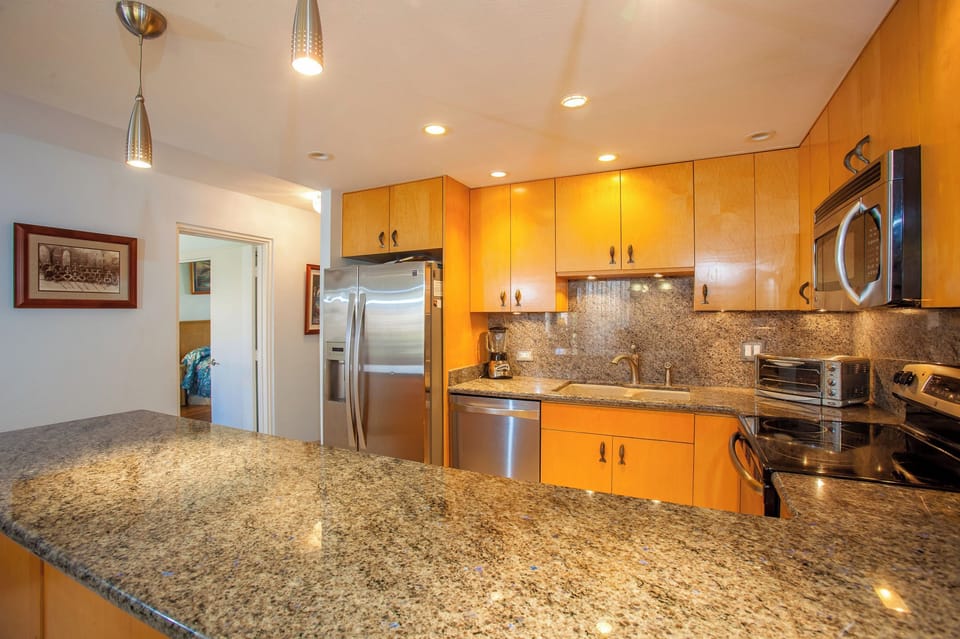 Your fully equipped modern kitchen features sleek granite countertops, stainless steel appliances, and warm wood cabinetry—perfect for preparing home-cooked meals during your stay.
