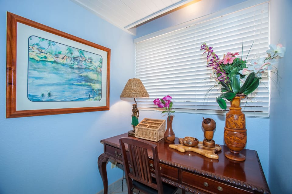 A tropical-inspired corner where coastal art and thoughtful decor create a relaxing retreat. Natural light filters through the blinds, highlighting handcrafted touches perfect for your island getaway.