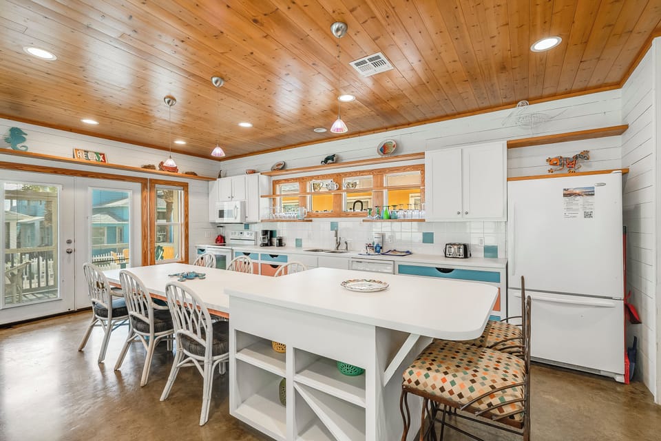 Gather around your spacious kitchen island where wood ceilings and coastal charm create the perfect setting for morning coffee and evening meals together.