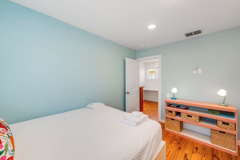 Unwind in your serene bedroom with soft mint walls and warm hardwood floors creating the perfect retreat after your day of exploring.