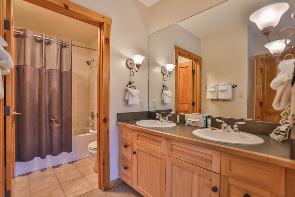 Refresh in your spacious dual-sink bathroom with warm wood vanities, modern fixtures, and thoughtful touches like soft towels.