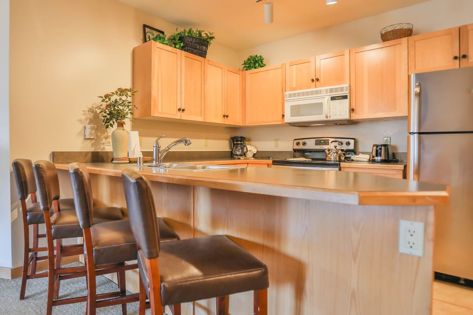Your fully equipped kitchen features warm wood cabinets, granite counters, and a breakfast bar where you can enjoy morning coffee.