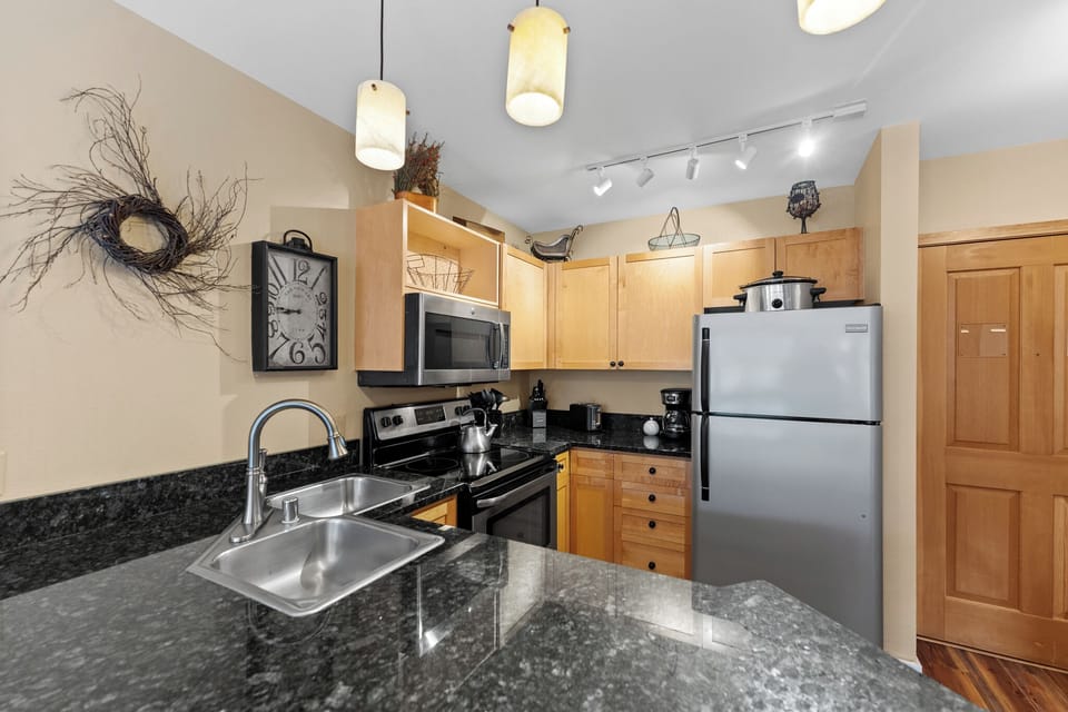 Cook your favorite meals in this fully-equipped kitchen featuring sleek granite countertops, stainless steel appliances, and warm wood cabinetry.