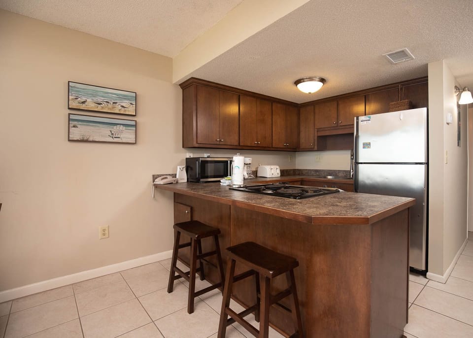 This kitchen features rich wood cabinetry, stainless appliances, and a convenient breakfast bar for casual dining