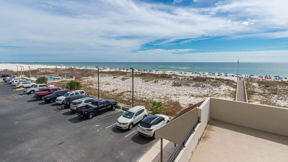 This view showcases a beautiful beachfront with sandy dunes and colorful umbrellas, perfect for relaxation and fun