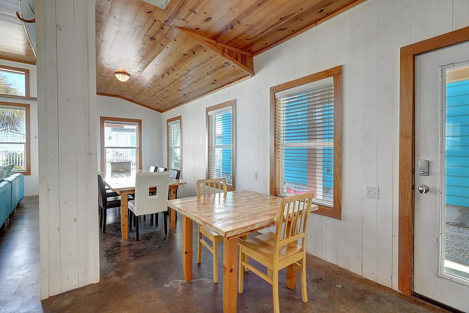 Gather around the warm wooden table in this bright dining space, where exposed beams and large windows create the perfect setting for memorable meals together.