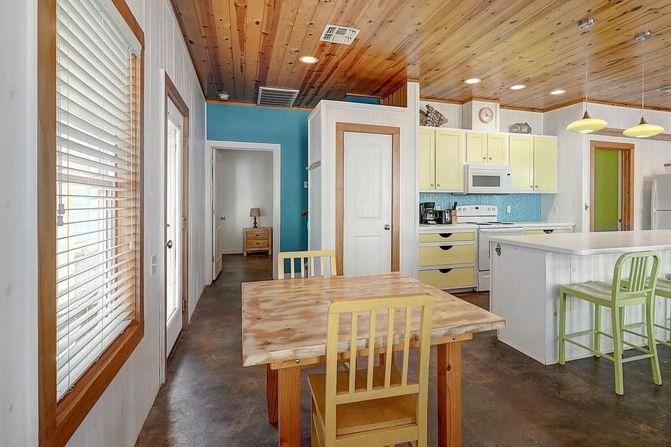 Your bright, open-plan kitchen invites memorable meals with rustic wood ceilings and cheerful touches throughout.