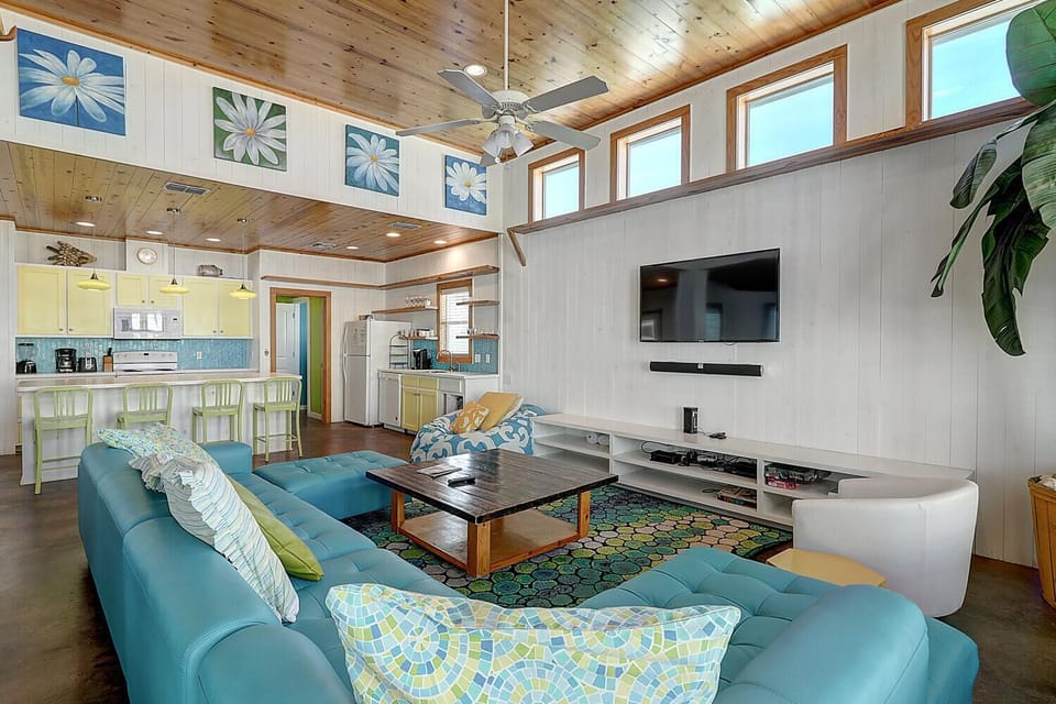 Sink into plush turquoise seating while enjoying your morning coffee in this bright, open living space with soaring wood ceilings and modern amenities.